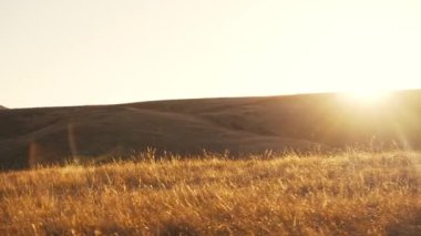 Gün batımında motosikletli bir adam dağlarda gezer.