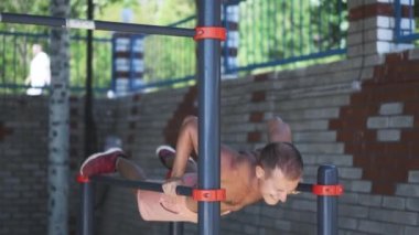 Sokaktaki paralel parmaklıklarda egzersiz yapan genç adam.