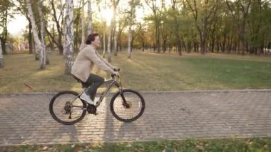 Halka açık parkta bisiklet süren neşeli yaşlı kadın.