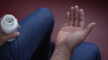 Elinde beyaz haplar tutan bir adam