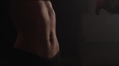 Karanlık odada güzel bir kadın göbeği.