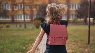 Pembe sırt çantalı kız okula koşuyor.