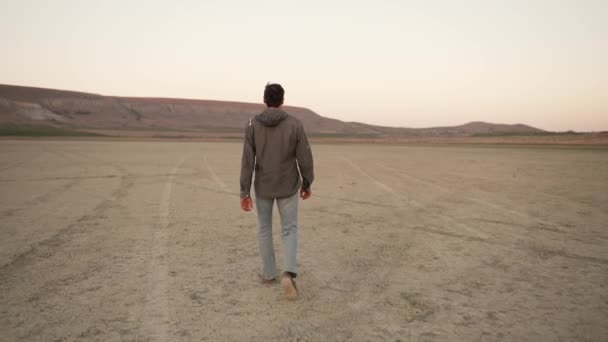 Bir Adam Gün Batımında Kuru Bir Gölde Yürür — Stok video