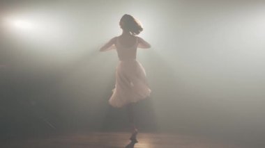 Siyah arka planda etek eteğiyle dönen büyüleyici bir balerin.