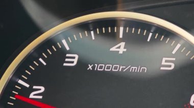 İğne kadranda hızla ilerlerken bir arabanın detaylı yakın plan görüntüsü dakikada bir devri gösteriyor.
