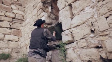 İki adam taş duvarların yanında büyük tahta bir sandık taşıyor..