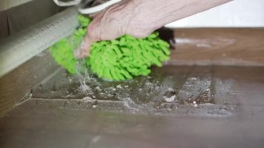 Bir kadın evini temizliyor ve bir bez parçası kullanıyor. Köşedeki ağır toprağı temizliyor..