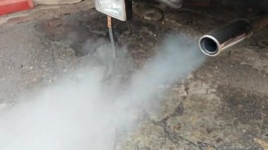 Eski bir arabanın egzoz borusu duman yayar, kirlilik belirtileri gösterir ve yıpranır.