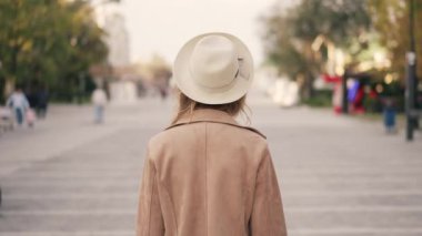 Sokakta dolaşan bir kadın, arkadan yakalanmış, gösterişli zarafet ve şehir hayatı sergiliyor.