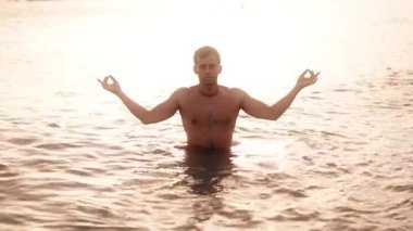 Günbatımında dinlenmek ve bilinçlenmek için sakin sularda meditasyon çalışması.