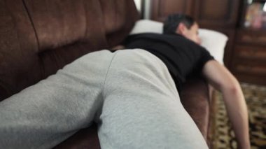A person relaxing on the couch, scratching his ass