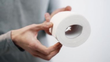 Bir rulo tuvalet kağıdı tutan adam, kullanılmaya hazırlanıyor..