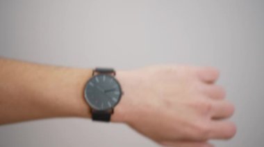 Bir erkeğin elindeki kol saatinin yakın çekimi, basit ve zarif bir tasarım..