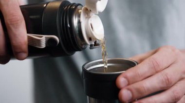 Termostan buharı tüten çay döken erkeklerin yakın çekimi.