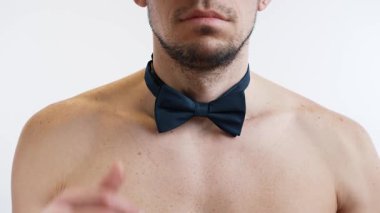 Çıplak göğüslü bir erkek model çıtır bir papyon takar.