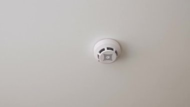 Beyaz bir tavana yerleştirilmiş modern bir yuvarlak duman dedektörü, yangın önleme sistemlerinde alarm hazırlığının ve kritik rolün sinyallerini veriyor.