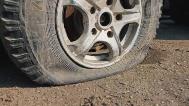 Asfaltta sönmüş bir araba lastiği, yol kenarında sorun ve tamir ihtiyacı vurgulanıyor..