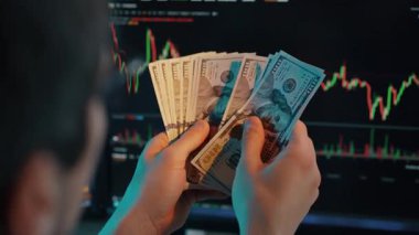 Nakitle ilgilenen ellerin yakın çekimi ve grafikleri gösteren bir monitör, veriye dayalı kararları ve ekonomik planlamayı sembolize ediyor.