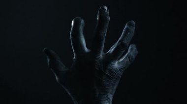 Yaşlanma efektleri olan dokulu bir el karanlıkta hafif hareket eder. Gizem uyandırmak için loş bir ışık. Cadılar Bayramı temaları veya tiyatro yapımları için idealdir..