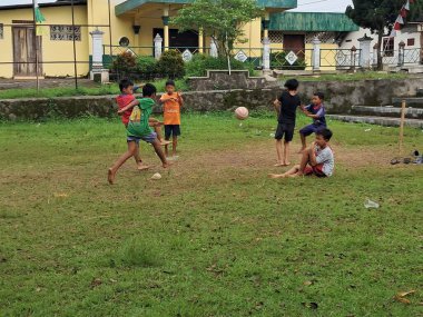 Çocuklar köy sahasında futbol oynuyorlar.