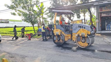 Gorontalo, 5 Ekim 2022, asfalt kaldırım taşı makinesi ve kamyon. Yol yapım ekibi asfaltın ilk katmanını uyguluyor. Sıcak asfalt asfalt döşeme ve yol çalışması - Yollu sıcak asfalt yolu düzleştir