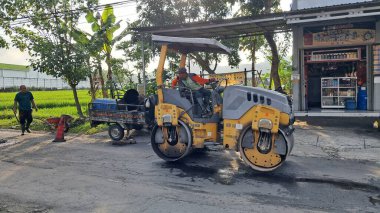 Gorontalo, 5 Ekim 2022, asfalt kaldırım taşı makinesi ve kamyon. Yol yapım ekibi asfaltın ilk katmanını uyguluyor. Sıcak asfalt asfalt döşeme ve yol çalışması - Yollu sıcak asfalt yolu düzleştir
