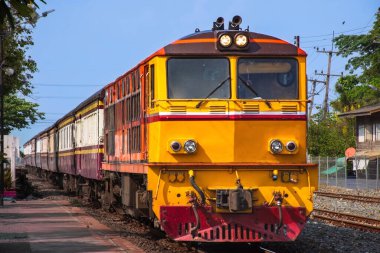 Tren istasyonunda dizel lokomotifle giden yolcu treni. Bina halka açıktır.)