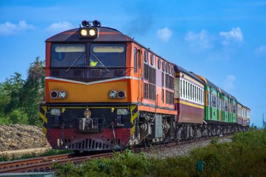 Passenger train by diesel locomotive on the railway in Thailand.