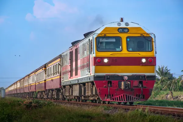 Passenger train by diesel locomotive on the railway in Thailand.