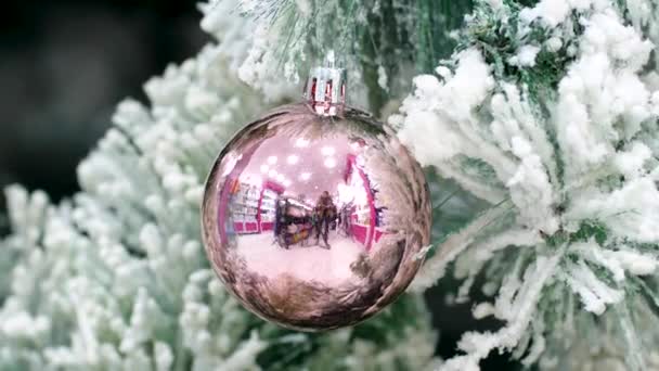 Een Pink Bauble Hangend Aan Een Kerstboom Met Sneeuwvlokken Reflectie — Stockvideo
