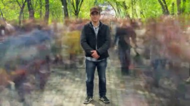 Arka plandaki yeşil ağaçlarda bulanık kalabalıkta tek başına duran adam. Zaman Kucakları. Tam HD