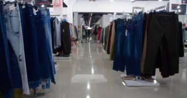 Moda mağazasında koridorda yürürken ve dikkatlice yerleştirilmiş kıyafet raflarının yanından geçerken çekilen kamera görüntüsü..
