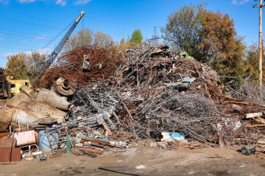 Arka planda vinç manzaralı hurda demir ve diğer çelik atık yığını.