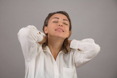 Güzel görünümlü bir kız, gözlerini kapatıyor, tatlı tatlı gülümsüyor, mutluluk, sevgi ve umut duygularını ifade ediyor, yakın plan ışık arka planı