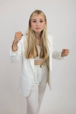 Uzun saçlı, açık renk elbiseli sarışın el hareketleriyle saldırganlık duygularını ifade ediyor. Beyaz arkaplanda yakın plan
