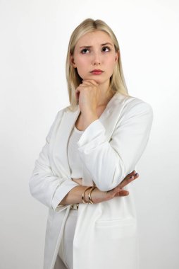 Sarışın, uzun saçlı, beyaz takım elbiseli, sakin ve derin düşünceli biri. Işık arkaplanına yakın plan.
