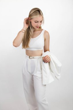 Beyaz elbiseli güzel sarışın model, arka planda kameraya poz veriyor..