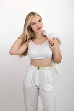 Beyaz bluzlu ve kameraya poz veren güzel gülümseyen sarışın bir gencin portresi. Işık arkaplanına yakın plan.