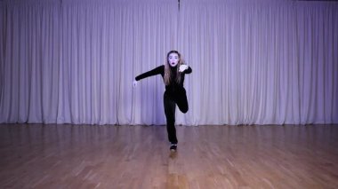 Pandomim sahnesi, iki uzun at kuyruklu sarışın pandomimci kız, yavaş bir düşüşe geçiş için hızlı bir adım gösteriyor, parlak renkli bir sahne..