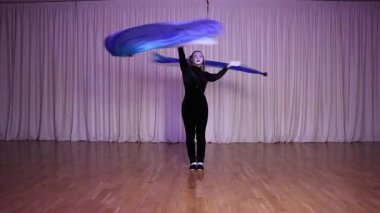 Pandomim sahnesi, iki uzun at kuyruklu sarışın pandomimci kız, poi 'nin uzun kumaşla, yanardöner renklerle çalıştığını gösteriyor. Işığın.