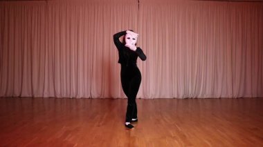 Bir aktris elinde beyaz bir maskeyle sahnede pandomim yapıyor..