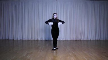 Bir pandomim oyuncusu parıldayan ışıklarla aydınlatılmış bir sahnede beyaz sirk toplarıyla hokkabazlık yapar..