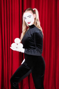 Tiyatro sahnesinde beyaz balonlarla pandomim sanatçısı. Kırmızı perdeye yakın çekim..