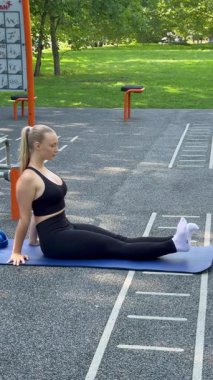 Bir sporcu kadın yerde otururken bacağını ısıtmak için egzersiz yapıyor.