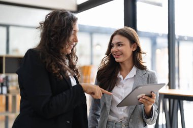 Çeşitli iş adamları birlikte çalışarak şirket mali istatistiklerini tartışıyor, çok ırklı meslektaşlar tabletteki finansman ile beyin fırtınası yapıyor