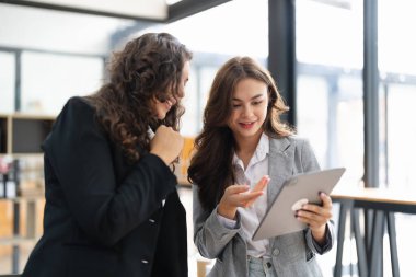 Çeşitli iş adamları birlikte çalışarak şirket mali istatistiklerini tartışıyor, çok ırklı meslektaşlar tabletteki finansman ile beyin fırtınası yapıyor