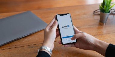 CHIANG MAI, THAILAND - 29 Haziran 2022: LinkedIn ekranlı iPhone 'a dokunan kadın. LinkedIn özgeçmiş oluşturulmasına ve yeni bir iş aranmasına yardımcı olur.