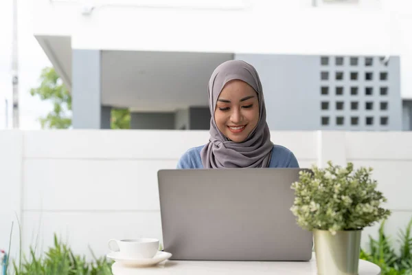 Portrait of Muslim asian woman in hijab using laptop at home