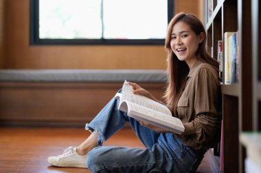 Kütüphanede kitap okuyan mutlu bir gencin portresi..