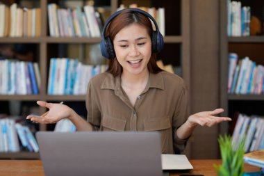 Asyalı dil hocası, stajyer el sallayarak bilgisayar ekranına bakarak online derse başlıyor. Uzaktan iletişim kuran kulaklıklı kadın, e-öğrenme süreci, uygulama kullanımı kavramı.